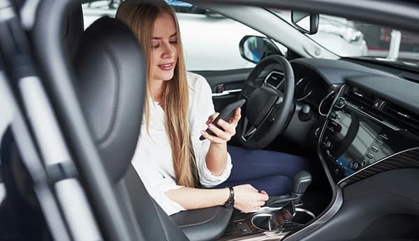 A professional checks her phone in a parked car before her next appointment