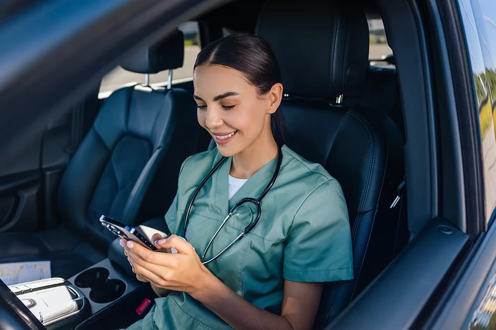 Healthcare professional in a car using a smartphone